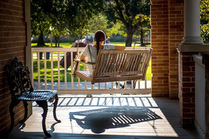 Student sitting on porch swing