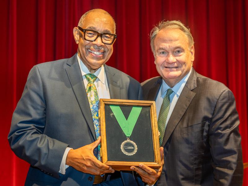 Doctor Michael White holding a framed medal with President Fitts