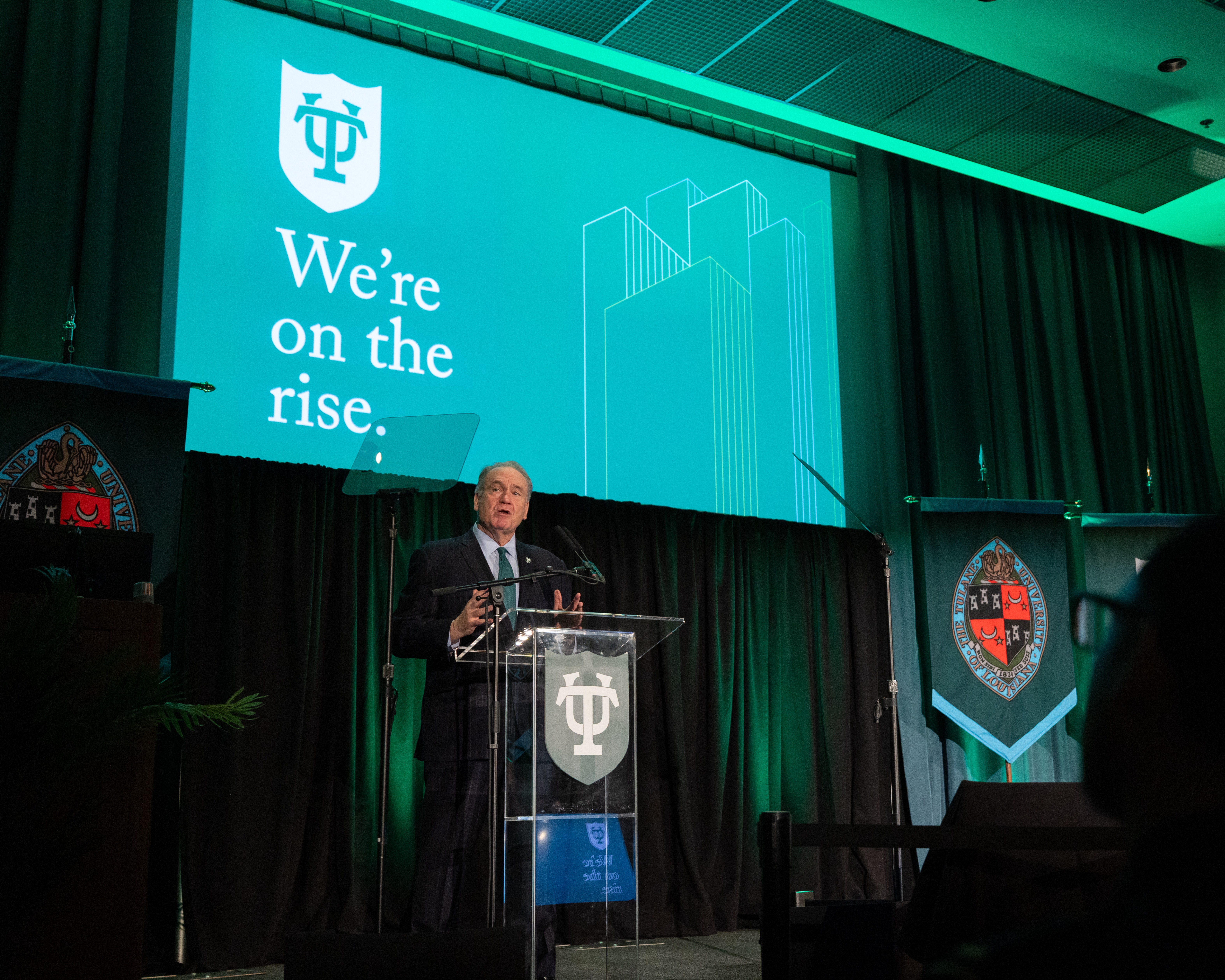 President Fitts speaks from a podium with slideshow behind him.