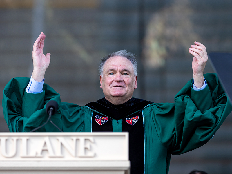 President Fitts with arms raised at podium for Commencement 2022
